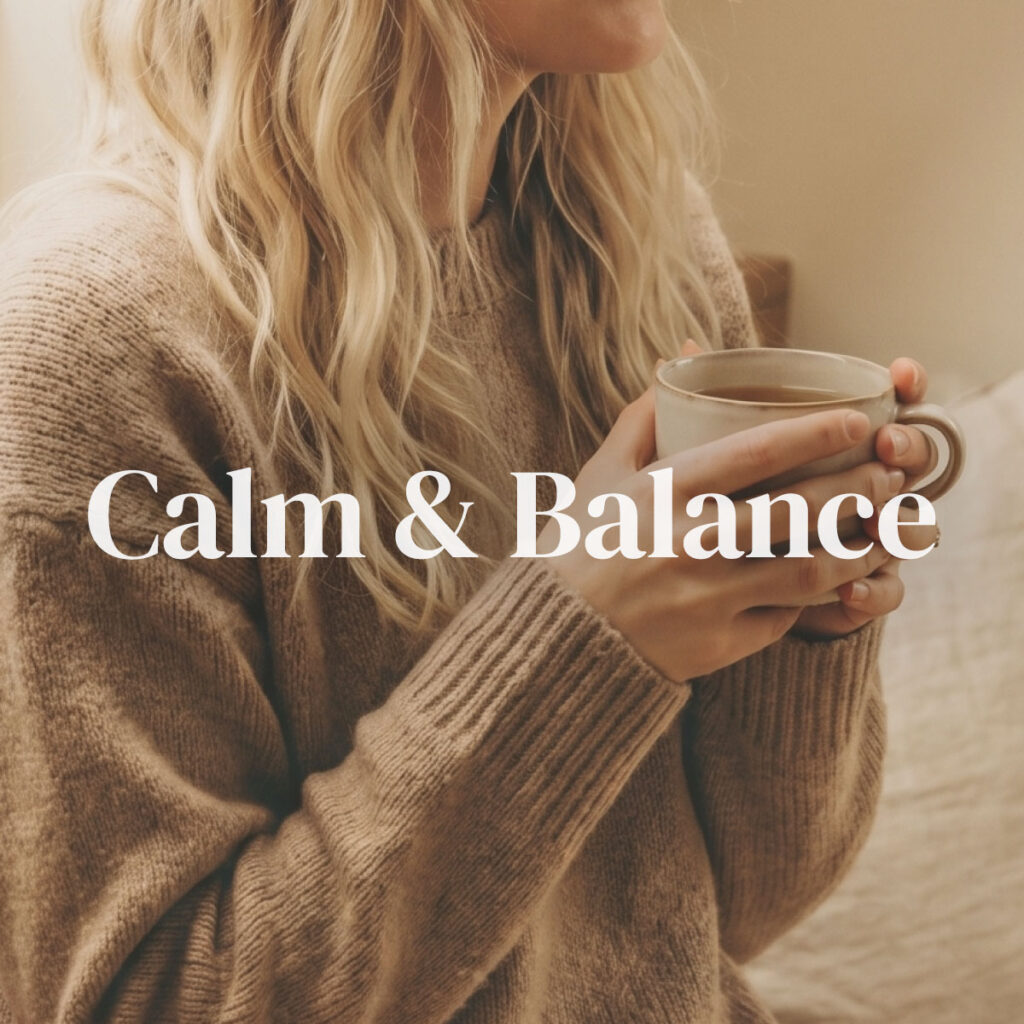 A blonde woman in a soft brown knit sweater cradling a warm ceramic mug with both hands in quiet morning light — representing the Calm & Balance category for stress relief, relaxation, and emotional well-being