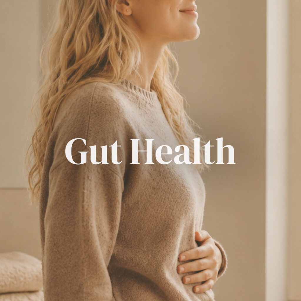 A woman standing in soft window light with one hand resting comfortably on her stomach and a peaceful expression — representing the Gut Health category supporting digestive comfort, bloating relief, and a balanced gut