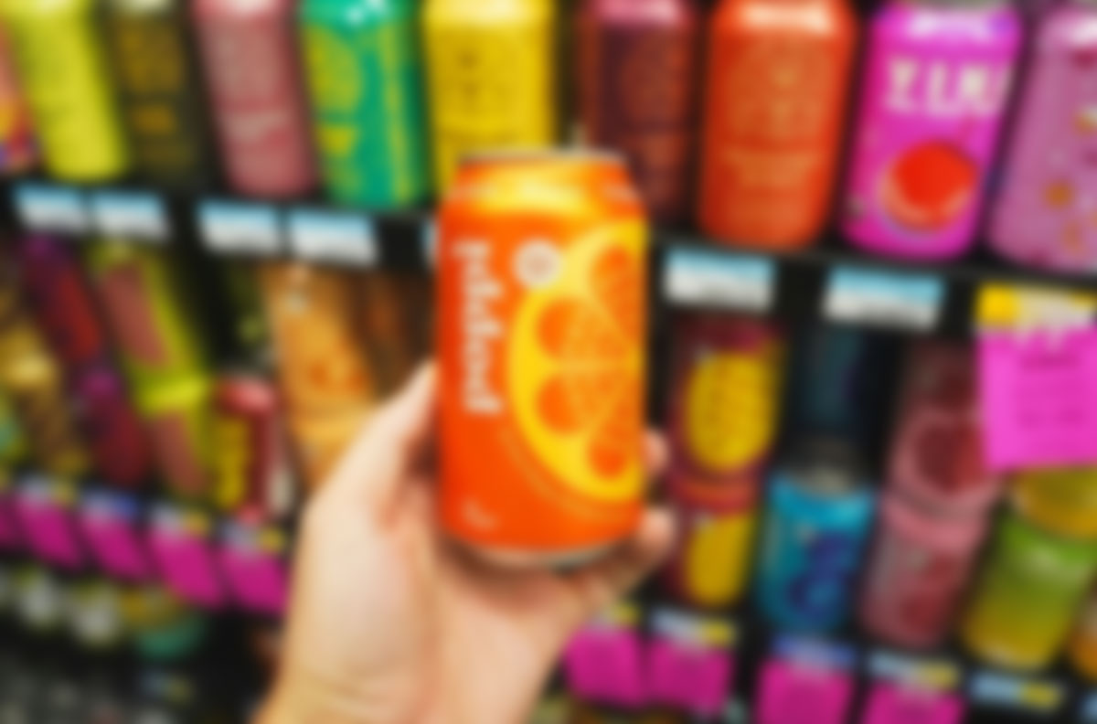 A hand holding a can of prebiotic soda, illustrating hidden ingredients that may trigger stomach pain and digestive discomfort.
