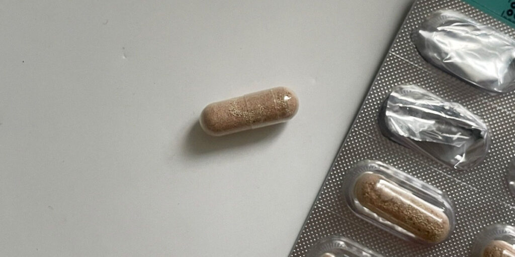 Close-up of a single probiotic capsule with visible yeast granules