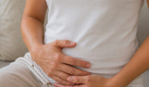 A person holding their lower abdomen while experiencing digestive discomfort.