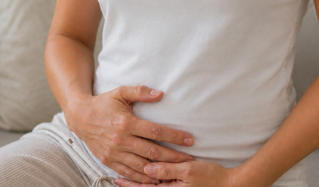 A person holding their lower abdomen while experiencing digestive discomfort.