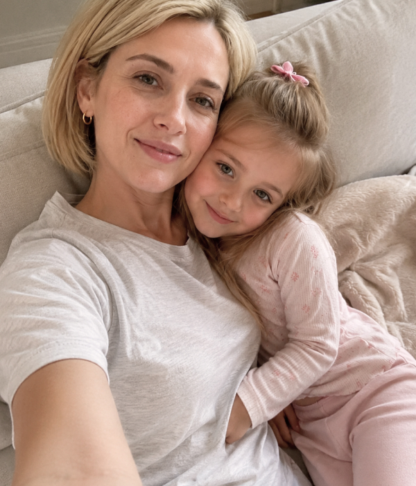 A pharmacist mom cuddling with her daughter on a sofa at home.