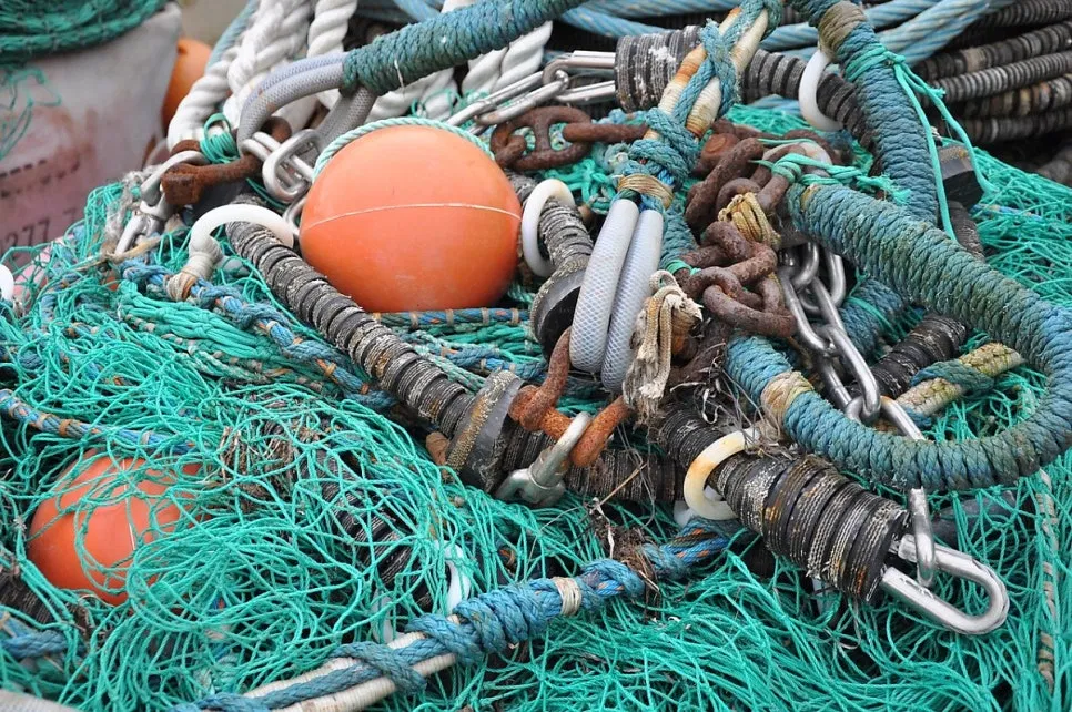 Tangled fishing nets, ropes, and orange buoys piled on a dock, representing concerns about heavy metal contamination in marine-sourced fish collagen