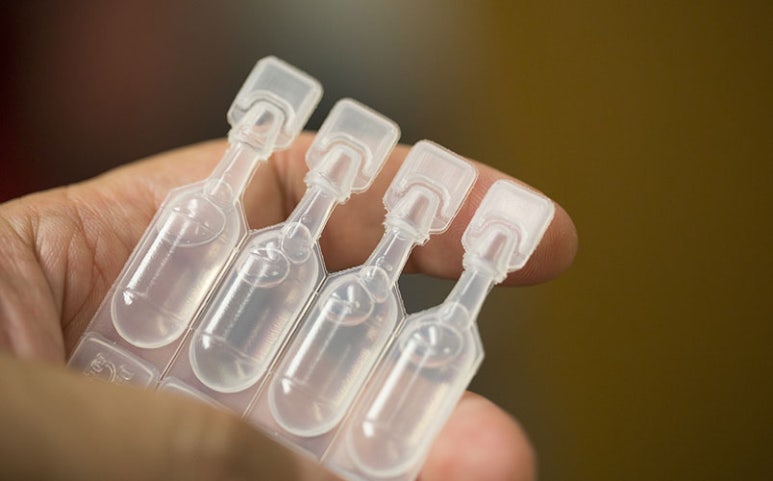 Hand holding four preservative-free single-use artificial tear vials