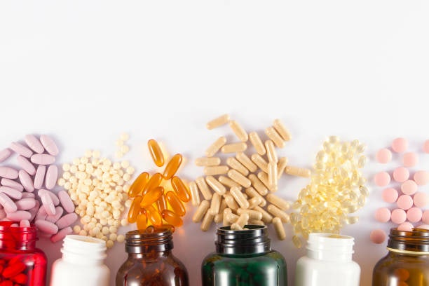 Assorted supplement capsules and tablets spilling from bottles onto a white surface