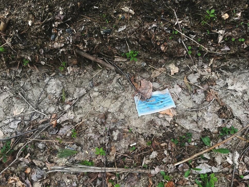 Discarded face mask lying on bare soil, representing the pollution behind soil depletion