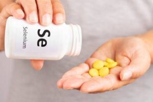 Selenium supplement tablets poured from a bottle into an open hand